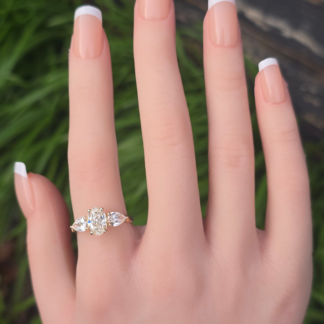 Gold ring with three lab grown diamonds oval & pear shaped on a woman's hand