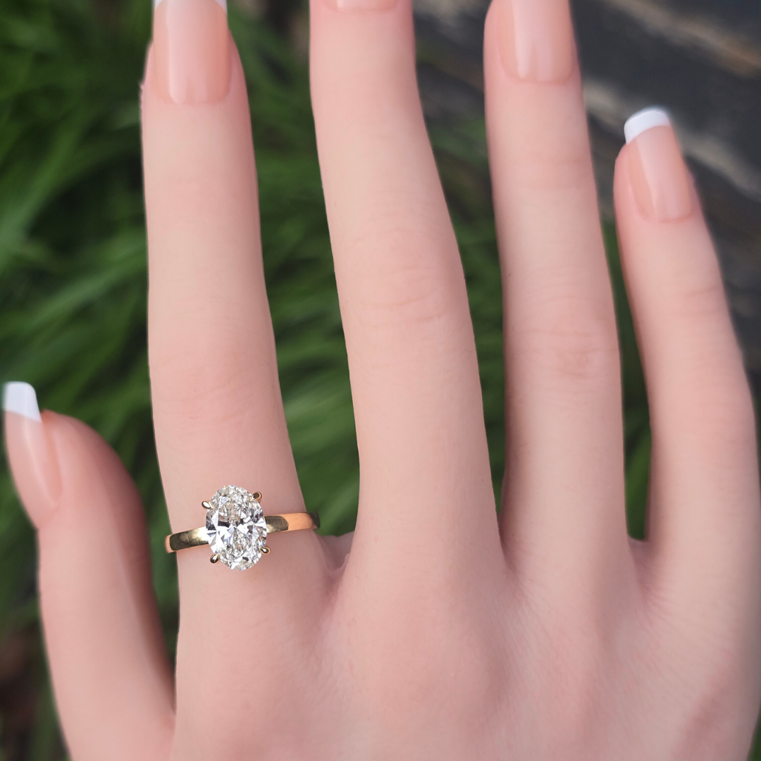 Oval lab grown diamond solitaire ring with accents worn on finger